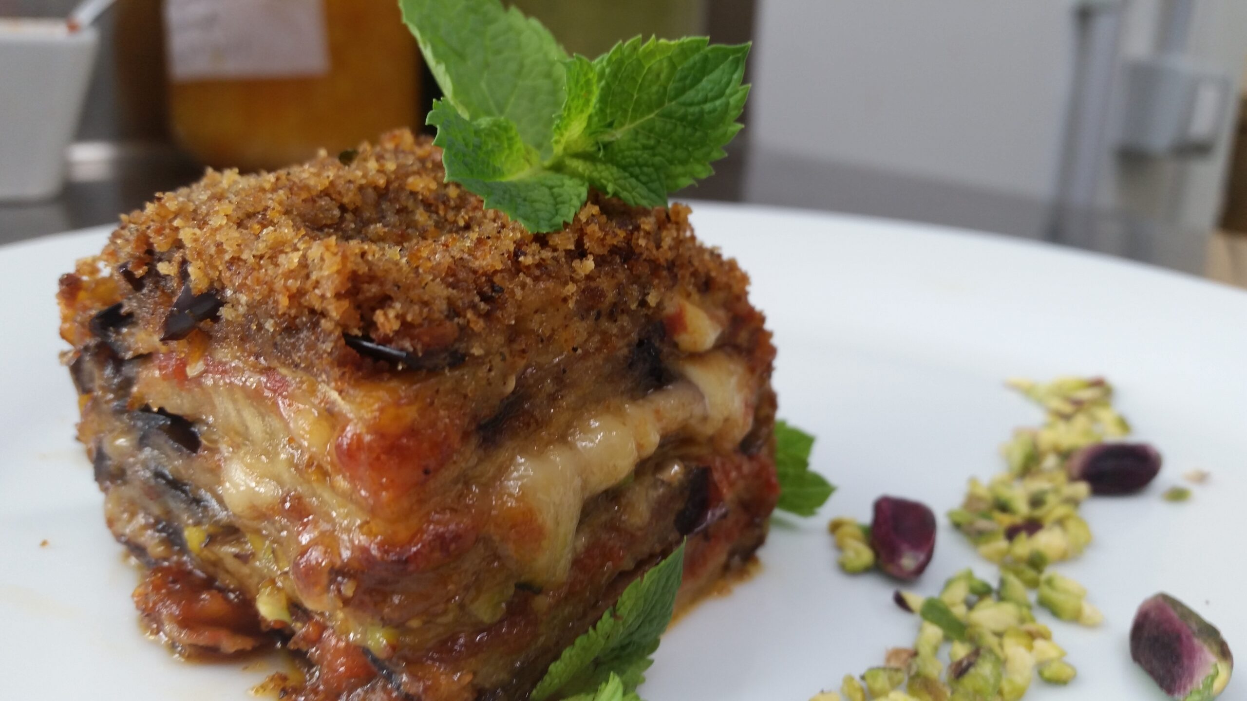 Monoporzione di parmigiana di melanzane con crosta di pistacchio e foglie di menta