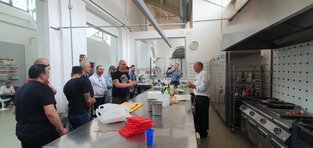 Salvo Nicastro, chef, spiega ai partecipanti durante una lezione di cucina per Conad in una cucina professionale