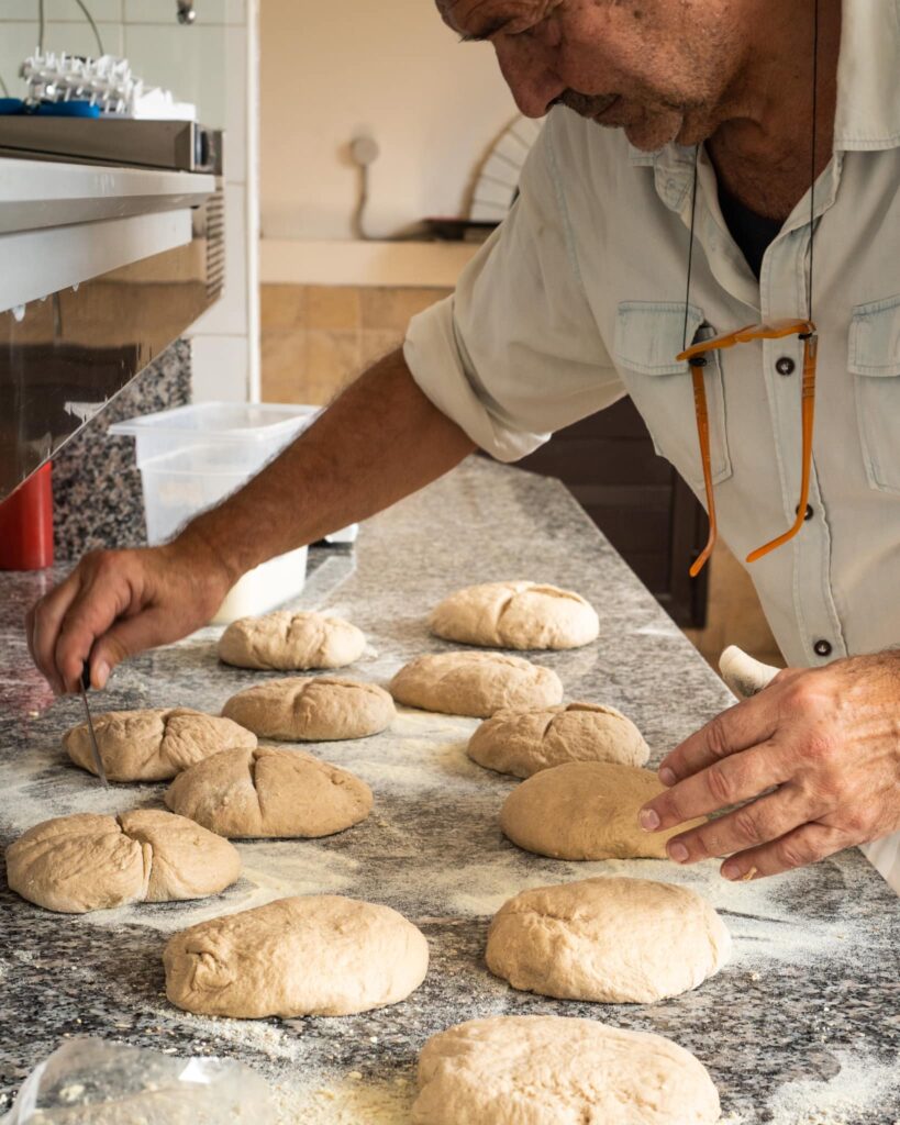 Un uomo forma a mano le pagnotte di pane a lievito madre sul piano di granito