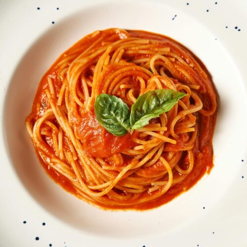 Spaghetti alla crudaiola con pomodoro fresco e basilico in un piatto bianco