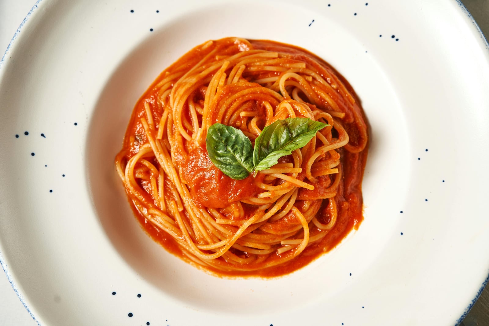 Spaghetti alla crudaiola con pomodoro fresco e basilico in un piatto bianco